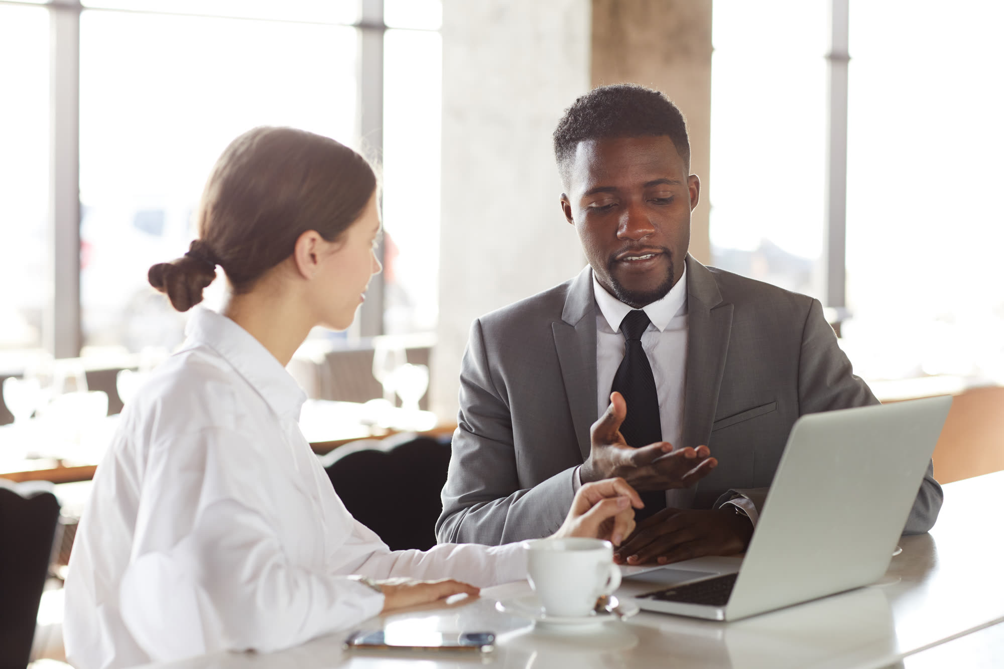 Black business consultant presenting a project on a laptop to a colleague