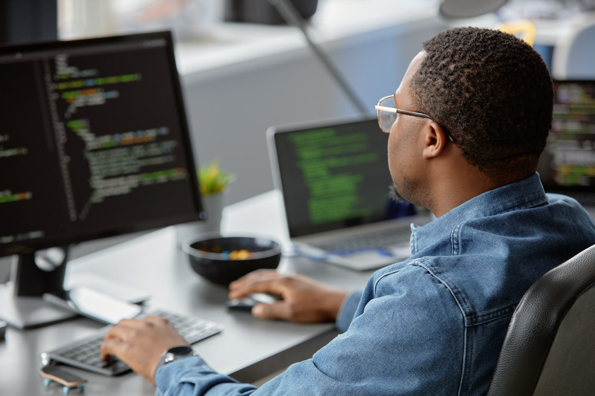 Programmer wearing glasses developing and maintaining website code