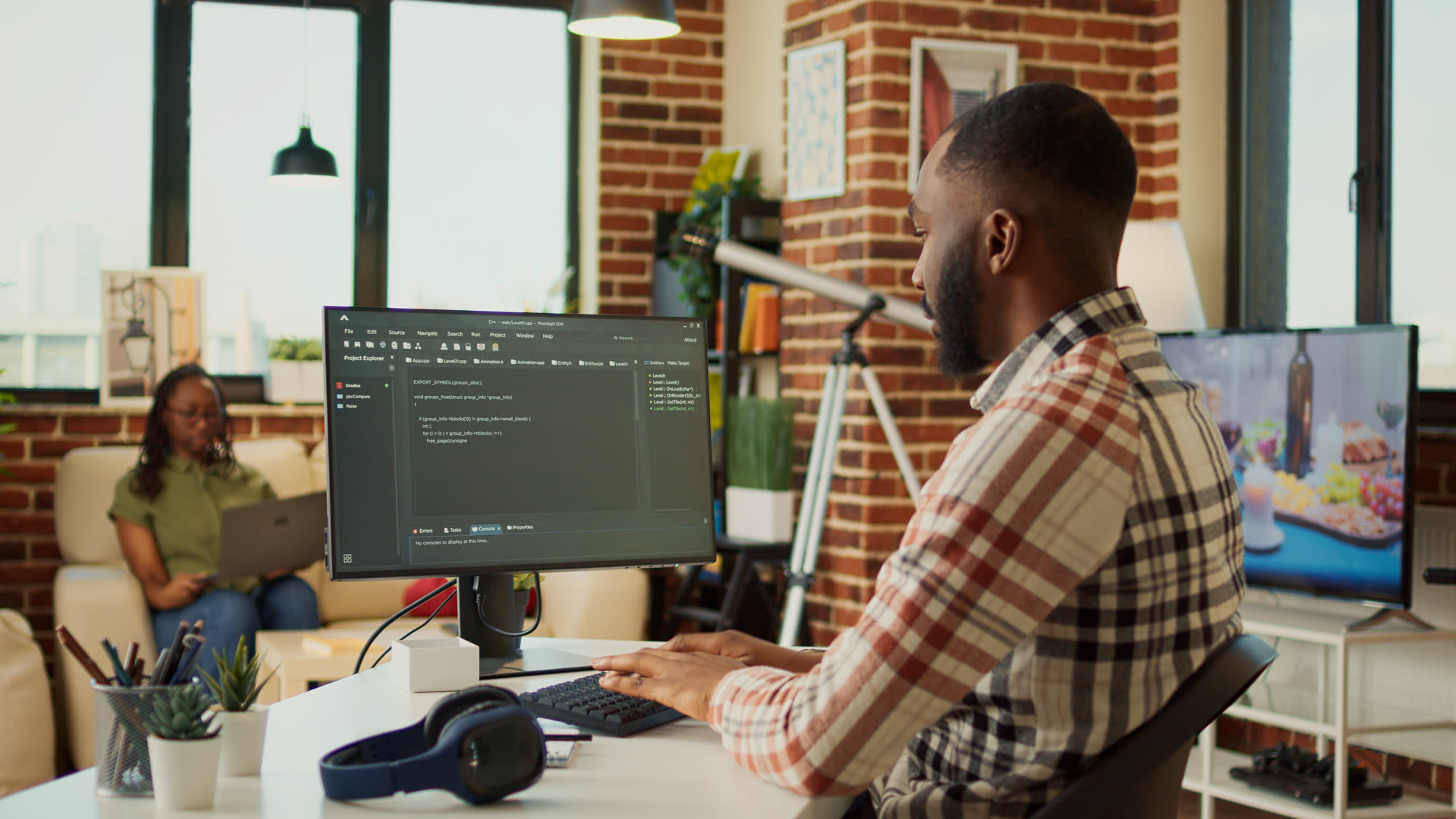 Male app developer writing HTML code on a laptop, working remotely on a web design project